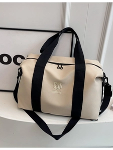 Grand sac de voyage beige et noir présenté sur un présentoir de style moderne