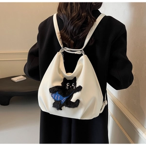 Détail du sac en cuir blanc cassé avec chat en peluche 3D et décor de poisson bleu