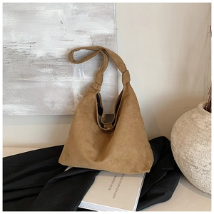 Detail of caramel suede tote bag featuring a minimalist knotted shoulder strap design
