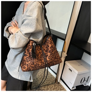Detail of leopard print tote bag featuring black leather straps and drawstring closure