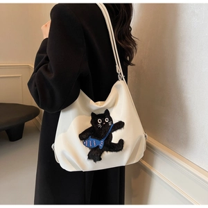Gros plan d'un sac cabas blanc avec broderie de chat 3D et petit poisson bleu