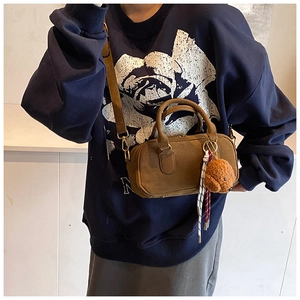 Dettaglio della borsa Boston in camoscio marrone con orsetto di peluche e corda
