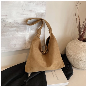 Close-up of brown suede hobo bag showing knotted strap and gold magnetic closure