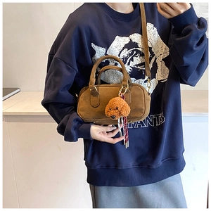 Dettaglio borsa Boston in camoscio marrone con ciondolo a cucciolo e tracolla
