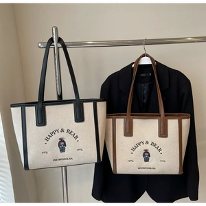 Detail of canvas tote bag with leather handles and bear print on stylish office wear background