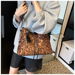 Close-up of leopard print tote bag featuring a leather Fashion tag and slim shoulder strap