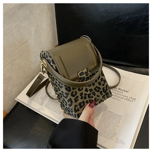 Detail of leopard print mini cylindrical crossbody bag with gold buckle and leather trim