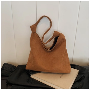 Detail of a brown suede tote bag featuring a minimalist knotted strap and magnetic closure