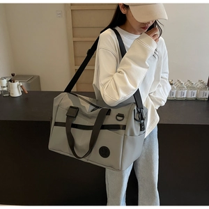 Grande borsa da viaggio grigia con manici rinforzati indossata da una modella