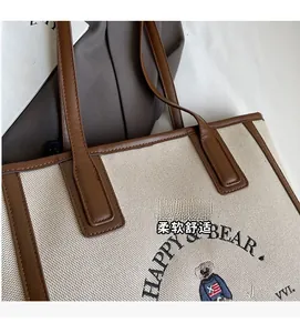 Detail shot of canvas tote bag with brown leather trim and cute bear graphic print