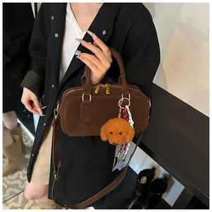 Dettaglio borsa Boston marrone opaca con hardware oro e ciondolo a cane