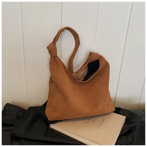 Close-up of brown suede tote bag featuring minimalist knotted strap and smooth texture