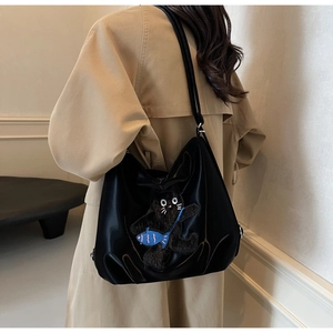 Détail d'un grand sac hobo noir avec broderie chat mignon et petit poisson bleu