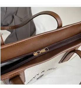 Detailed close-up of smooth gold zipper and leather trim on canvas tote bag
