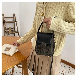 Detail of leopard print crossbody bag with black leather flap and gold hardware accents
