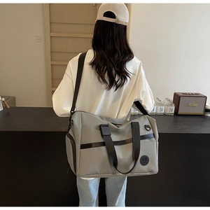 Dettaglio del borsone da viaggio grigio con tessuto in nylon resistente e logo in pelle