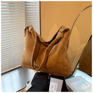 Detail of a brown suede tote bag featuring a creative knot strap and soft matte texture