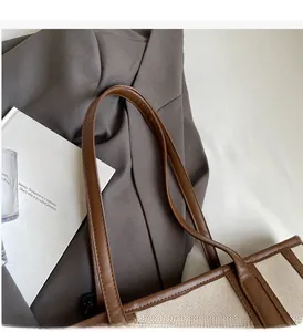Close-up of canvas tote bag with brown leather handles and reinforced stitching details