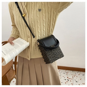 Detail of leopard print crossbody phone bag with black leather trim and metal clasp