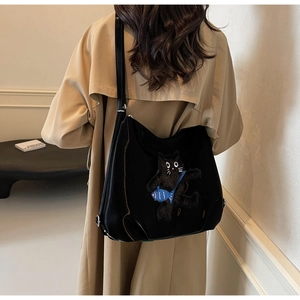 Gros plan du sac cabas noir brillant avec broderie de chat mignon et détail de poisson