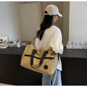 Dettaglio della borsa da viaggio kaki con manici neri e toppa rotonda con logo sul tessuto