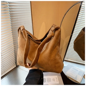 Close-up of brown suede tote bag featuring a unique knotted handle design for autumn