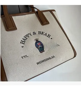 Detailed close-up of embroidered bear and letters on large canvas tote bag