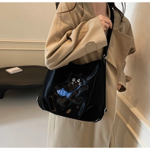 Détail du sac fourre-tout noir brillant avec motif chat floqué et breloque poisson