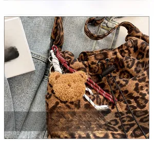 Detail of leopard print velvet bucket bag with plush bear charm and woven rope