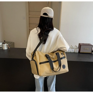 Dettaglio della borsa da viaggio kaki con scomparto per scarpe indossata da modella