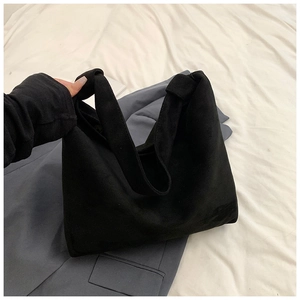 Detail of minimalist black tote bag with decorative knot handle and soft suede texture