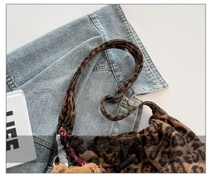 Macro view of leopard print shoulder bag with adjustable knotted strap and bear charm