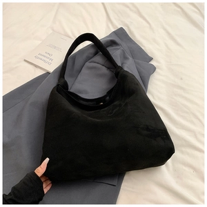 Detail view of large black matte tote bag with magnetic clasp on grey blazer background
