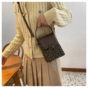 Leopard print crossbody bag with brown leather flap and metal clasp on beige knit outfit