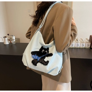 Détail du sac hobo en nylon bleu clair avec broderie chat noir mignon sur le devant