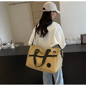 Dettaglio della borsa da viaggio kaki con manici in nylon nero e toppa con logo rotondo