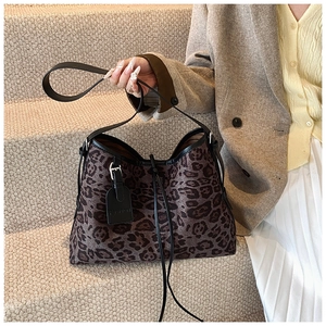 Detail view of the leopard print tote bag featuring black leather trim and logo tag