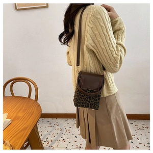 Brown crossbody phone bag with leopard print accent shown in a lifestyle home setting