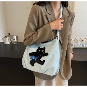 Gros plan d'un sac bandoulière bleu clair orné d'une broderie de chat noir en peluche