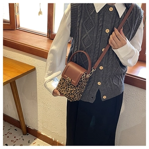 Detailed view of leopard print mini crossbody bag with leather trim and gold hardware