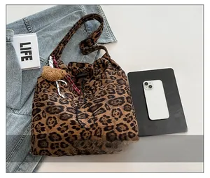 Leopard print bucket bag with drawstring closure and plush bear charm shown with a smartphone