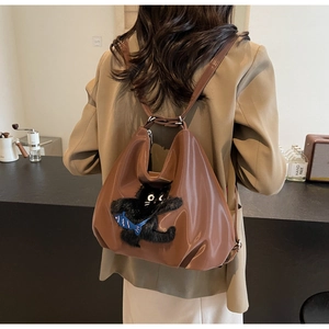Détail d'un sac à dos en cuir marron avec motif de chat en peluche et poisson bleu