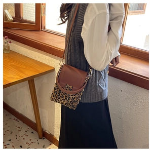 Detailed side view of leopard print crossbody bag with brown leather accents and metal buckle