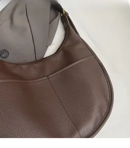 Close-up of deep brown litchi grain leather texture on a hobo crossbody bag