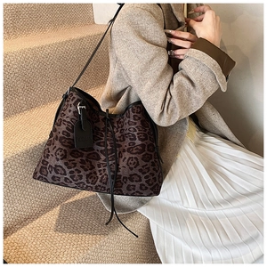 Detail of leopard print tote bag featuring a black leather tag and drawstring decor