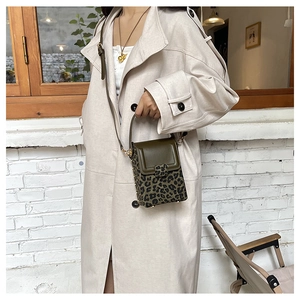 Mini leopard print crossbody bag with green flap shown on model wearing beige trench coat