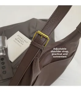 Close-up of brown leather bag with adjustable shoulder strap and brass buckle detail
