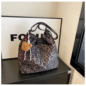 Detail of leopard print bucket bag with drawstring and plush bear accessory