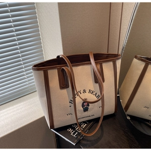 Detail of canvas tote bag with bear graphic and leather trim in a stylish interior setting