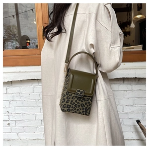 Detailed view of mini crossbody bag featuring olive green leather flap and leopard print texture